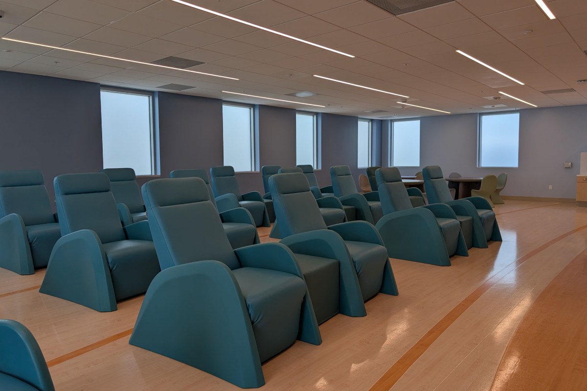 Rows of large blue reclining chairs are in a clean, empty medical room.