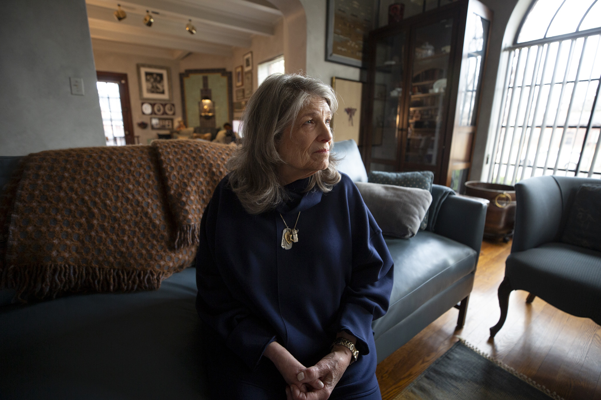 A woman sits on a couch in her home.