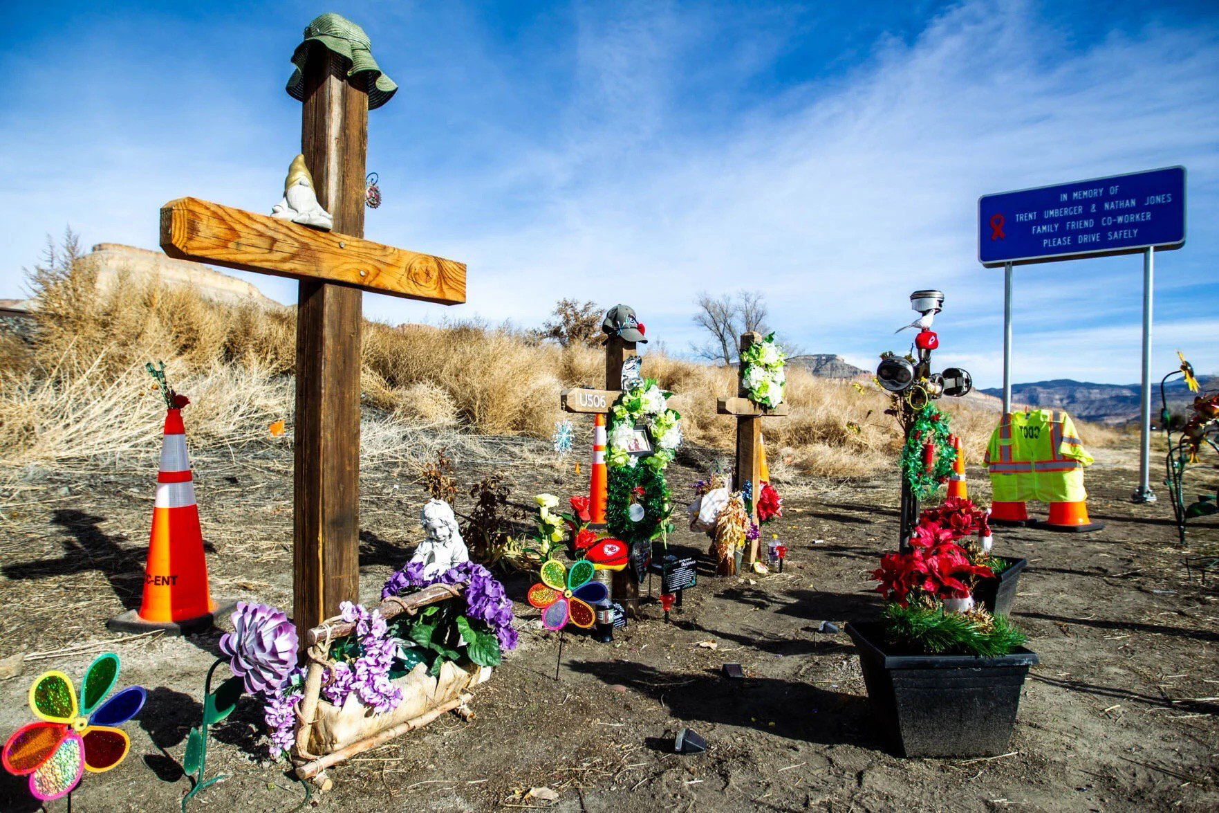 Wooden crosses adorned with flowers and other colorful objects of affection surround a small row of graves.