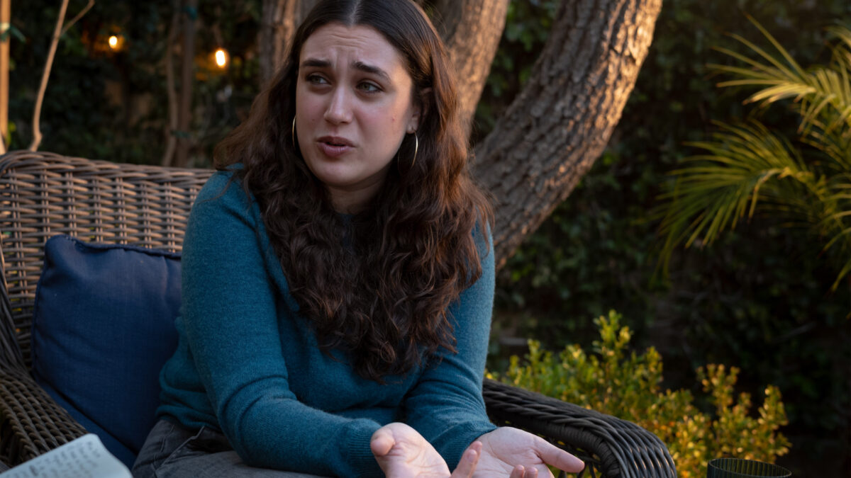 Mia Tretta speaks to someone out of frame to the left. The two are sitting outside.