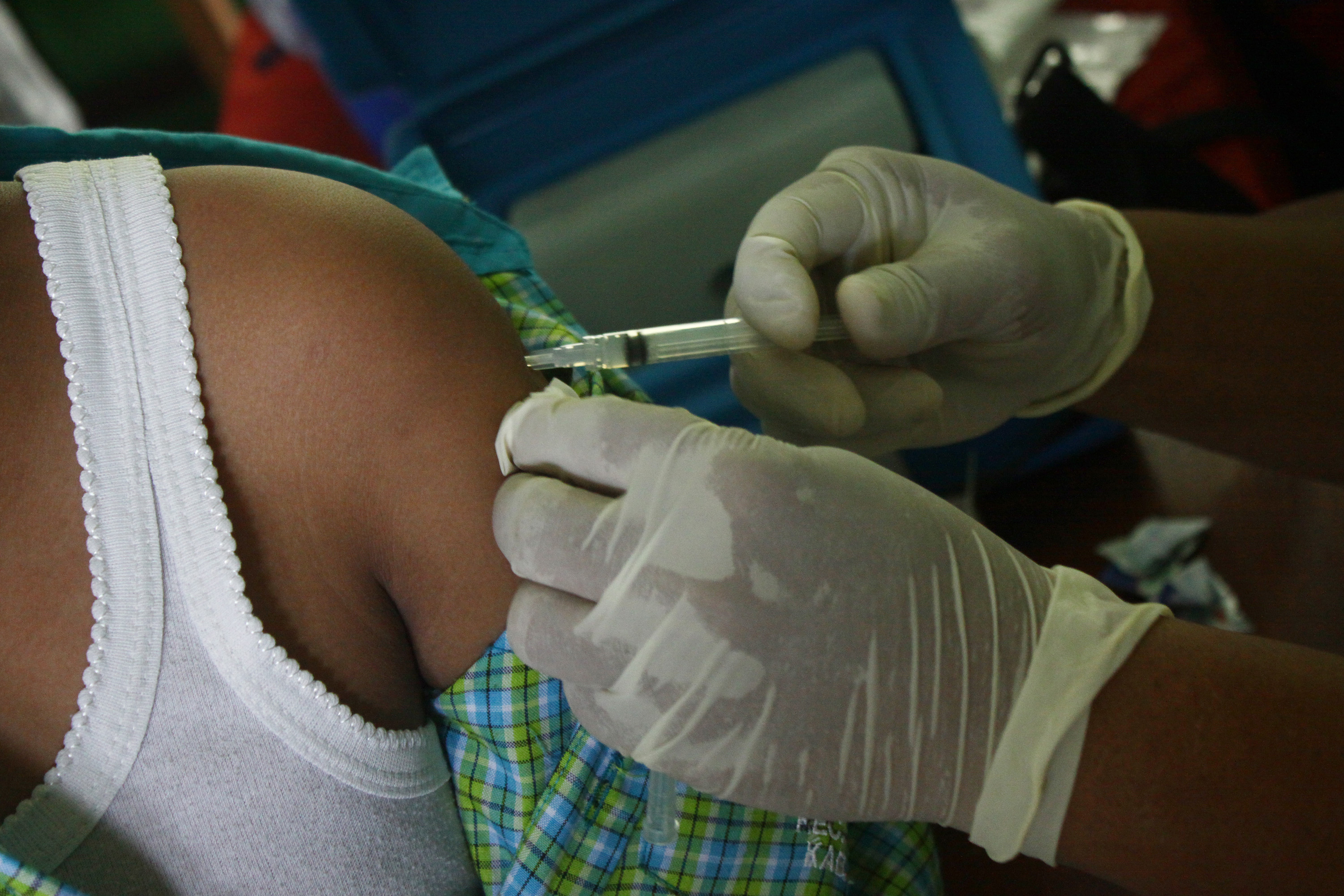 A syringe is inserted into a young Indonesian child's arm.