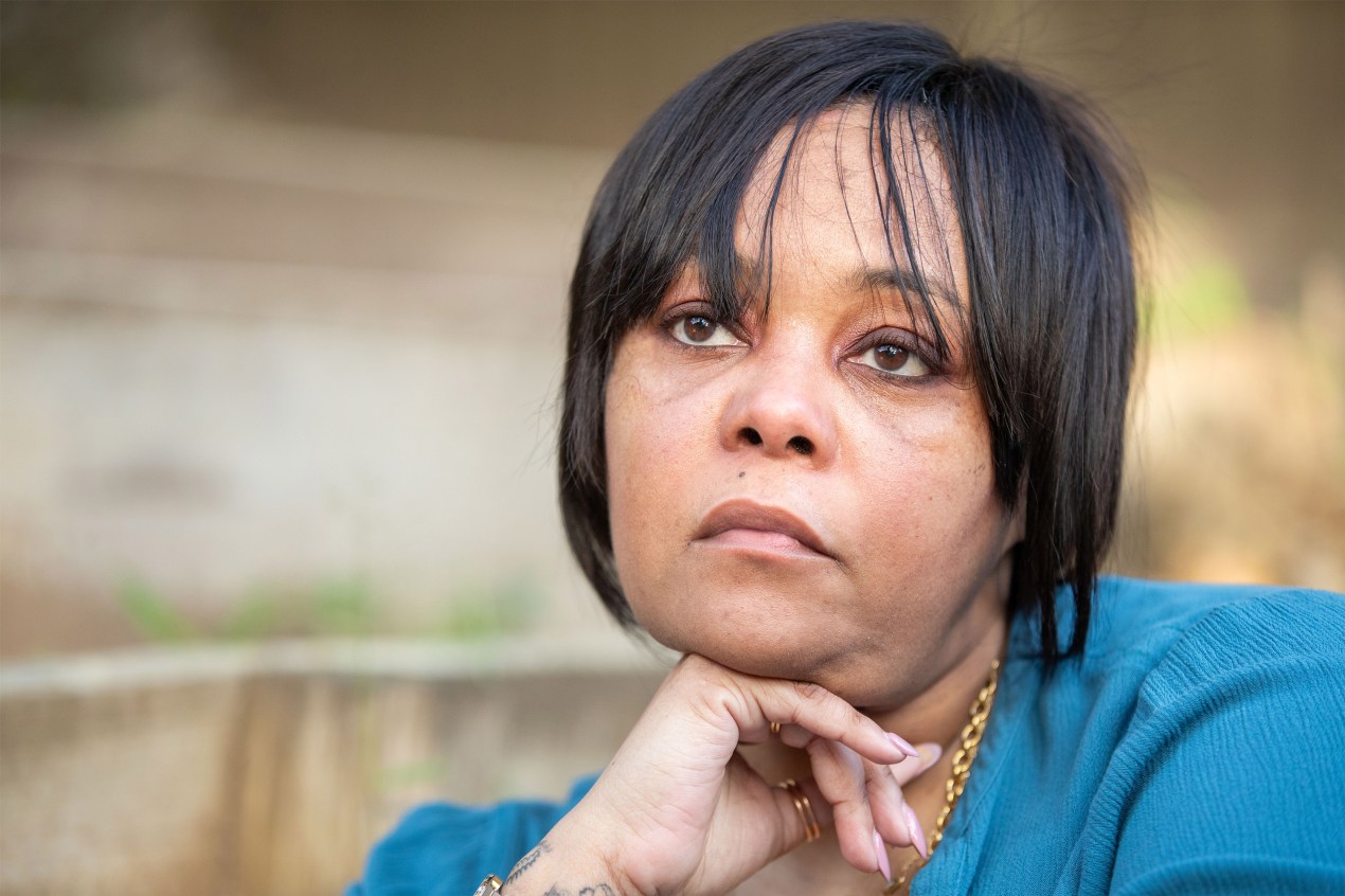 Alea Bates rests a hand on her chin, sitting for a portrait outside.