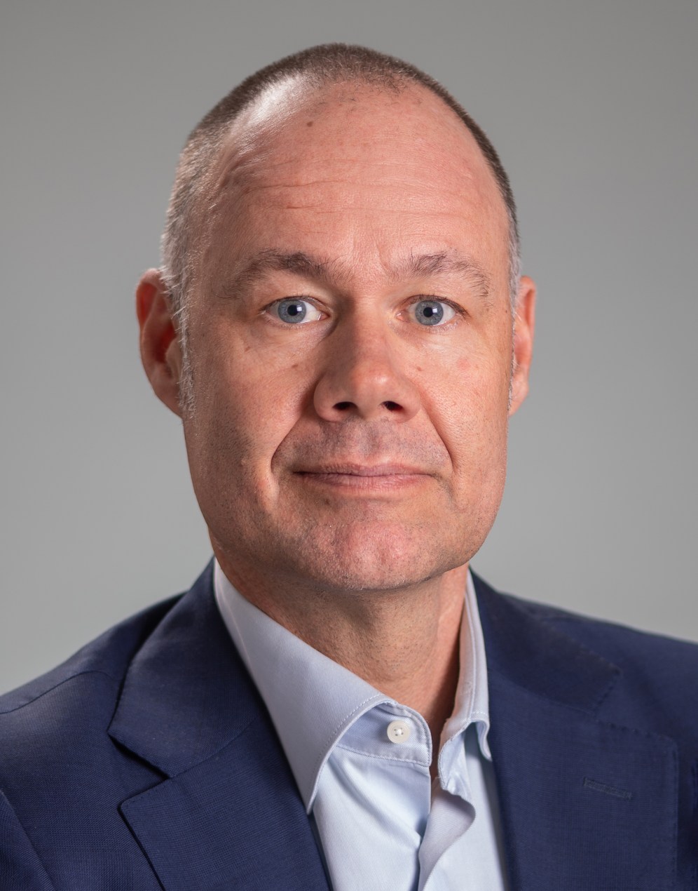 A portrait of a man with blue eyes and a navy suit