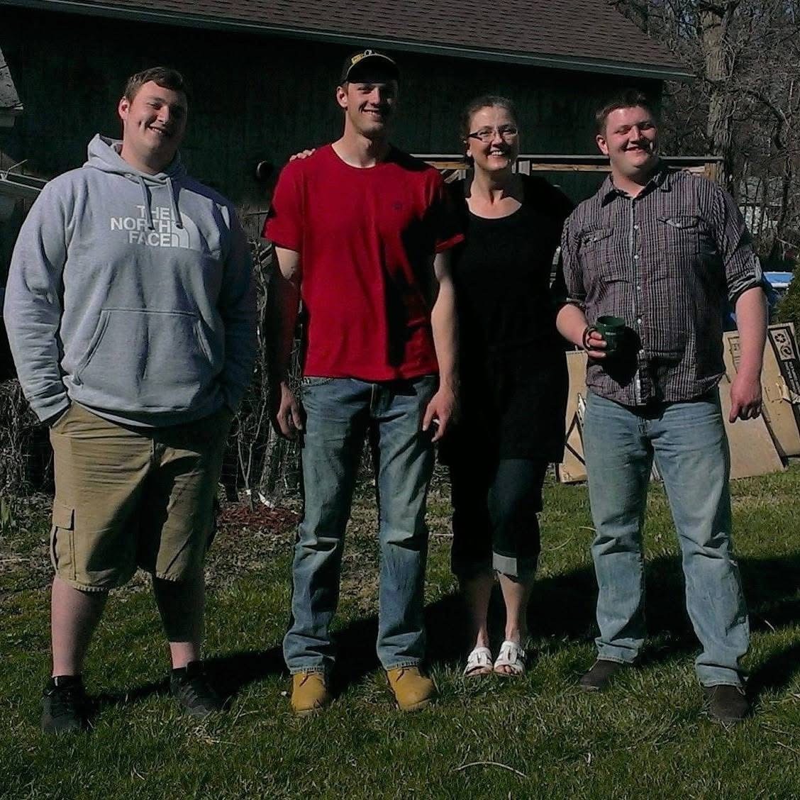 Three men and a woman stand outside an pose for a photo together.
