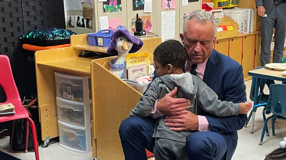 Robert F. Kennedy Jr. hugs a child at a childcare center.
