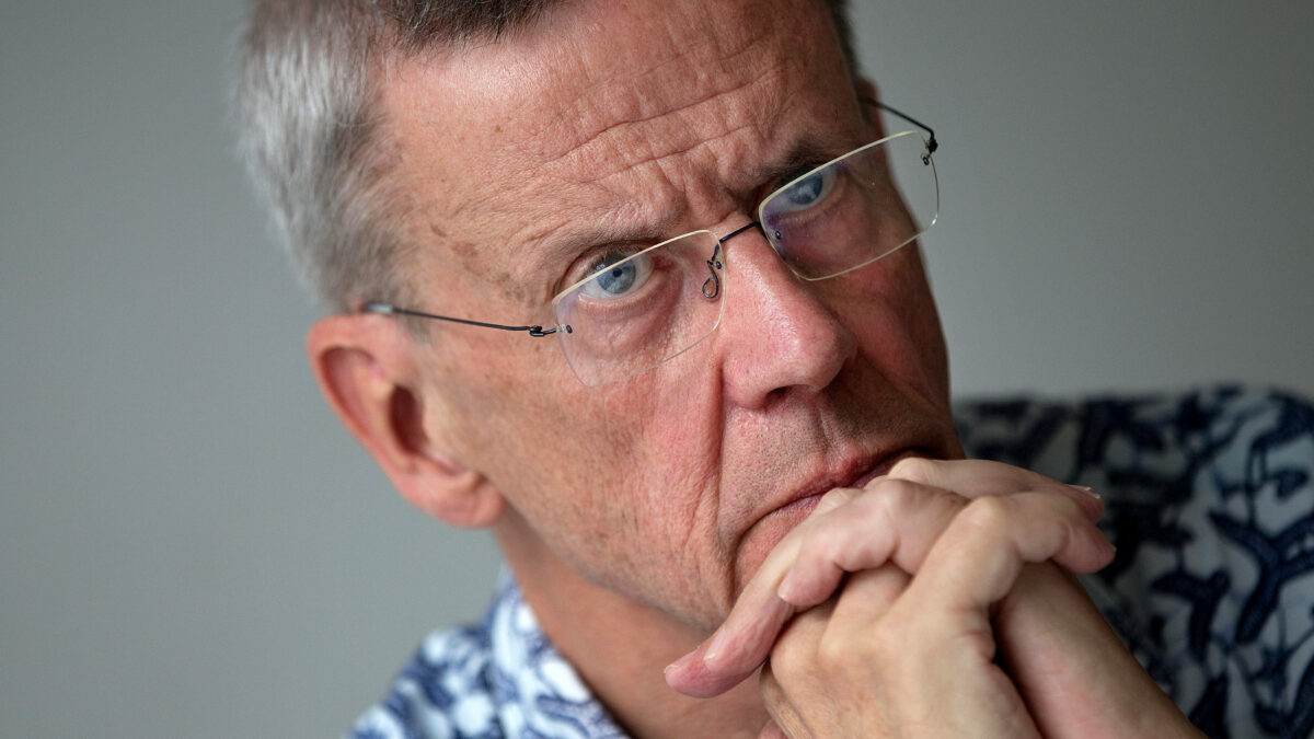 Peter Aaby sits at a table with his hands clasped. He rests his hands against his chin.