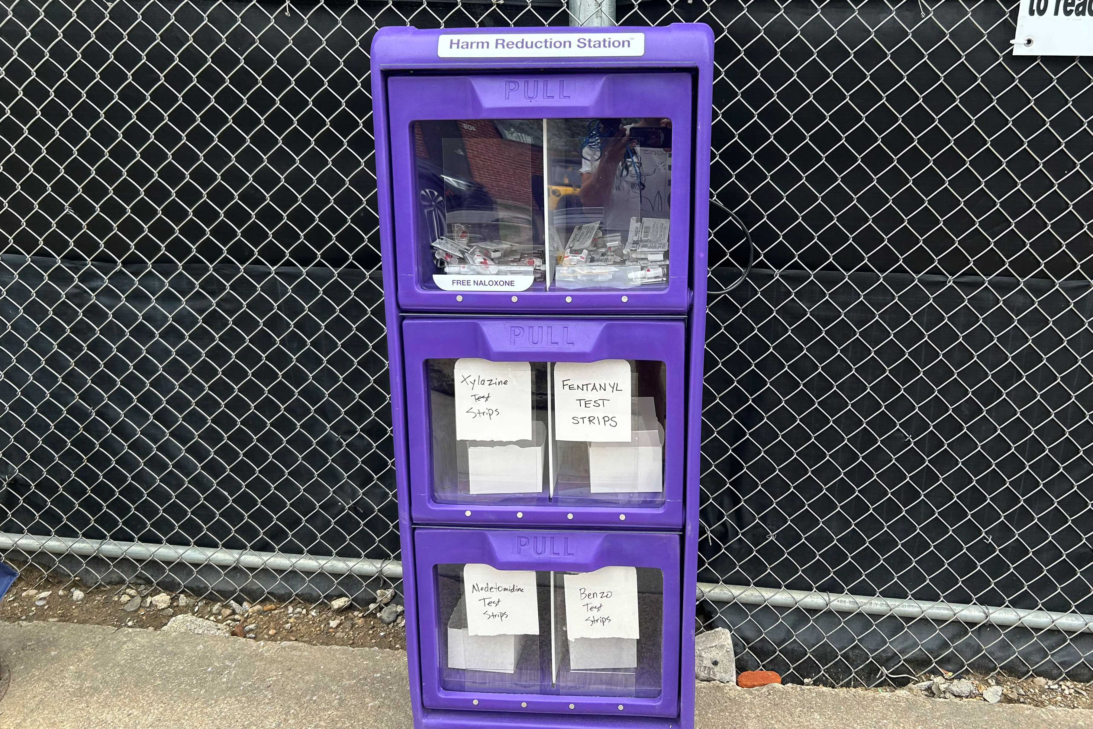 A photo of a purple storage container with clear drawers. The drawers are labeled: "Free naloxone, xylazine test strips, fentanyl test strips, medetomidine test strips, benzo test strips."