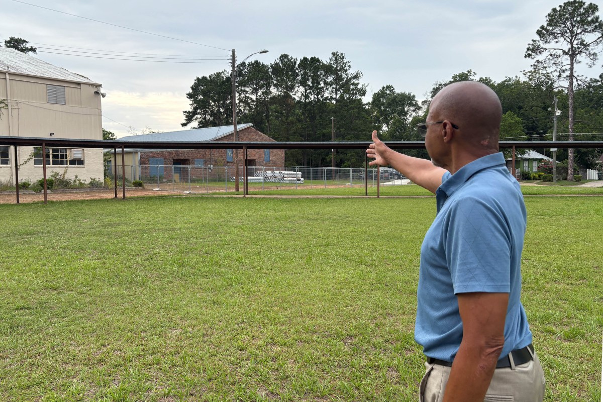 A photo of Earl Williams pointing to an old high school building.