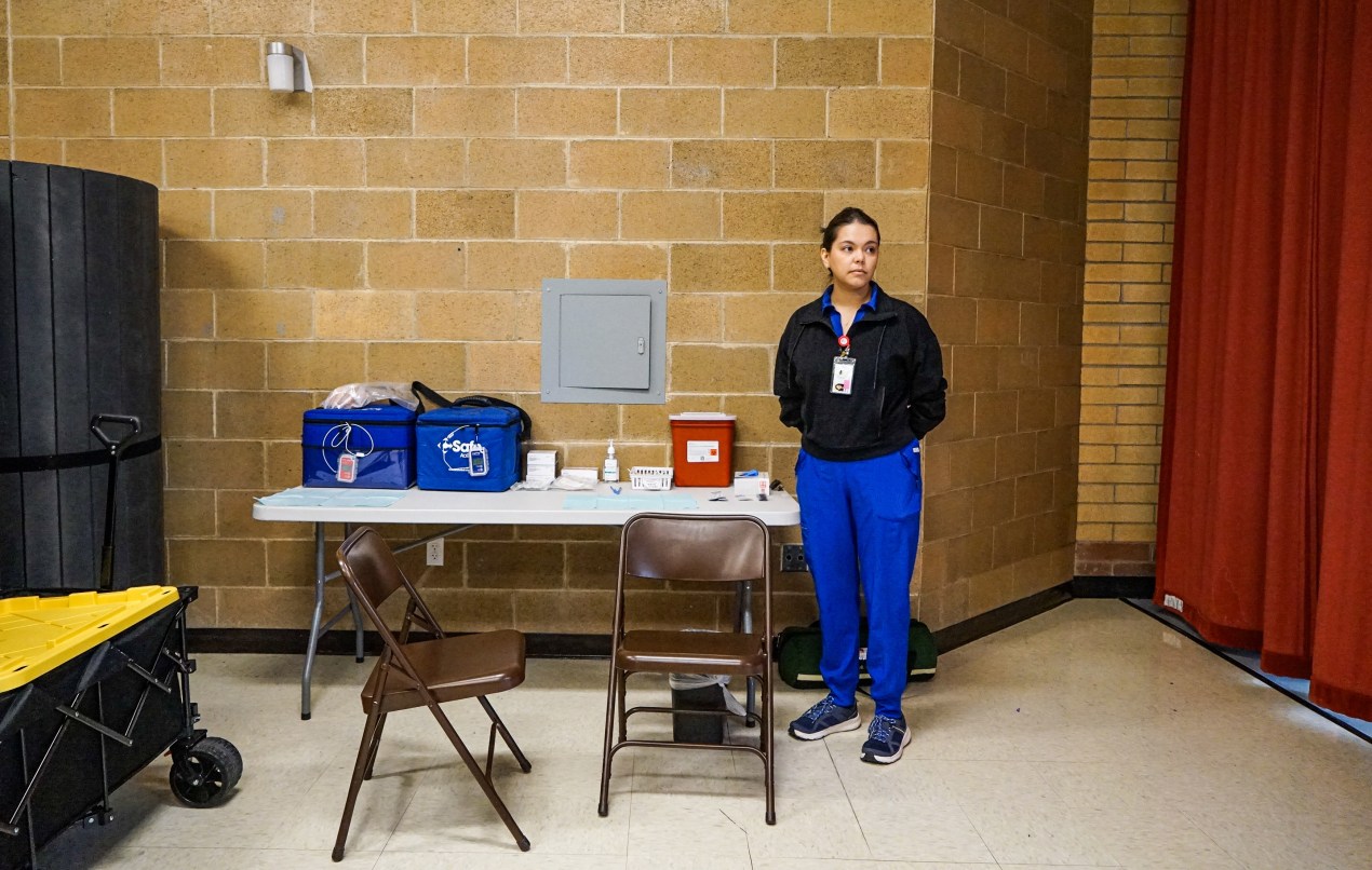 utahmeasles_06 A photo of a nurse standing by a folding table inside of a school.